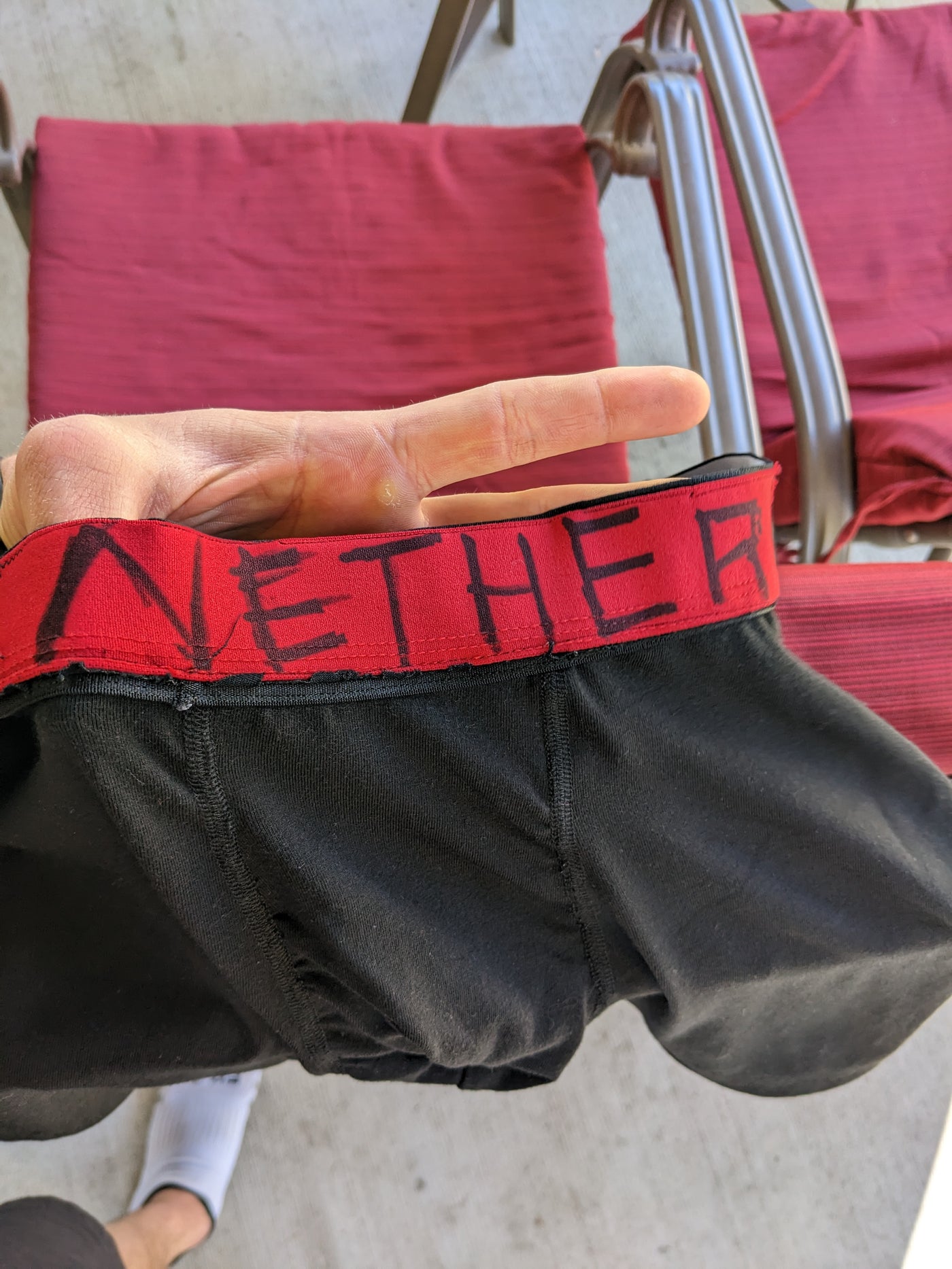 A homemade prototype held up by its red waistband, NETHER written across it in black marker