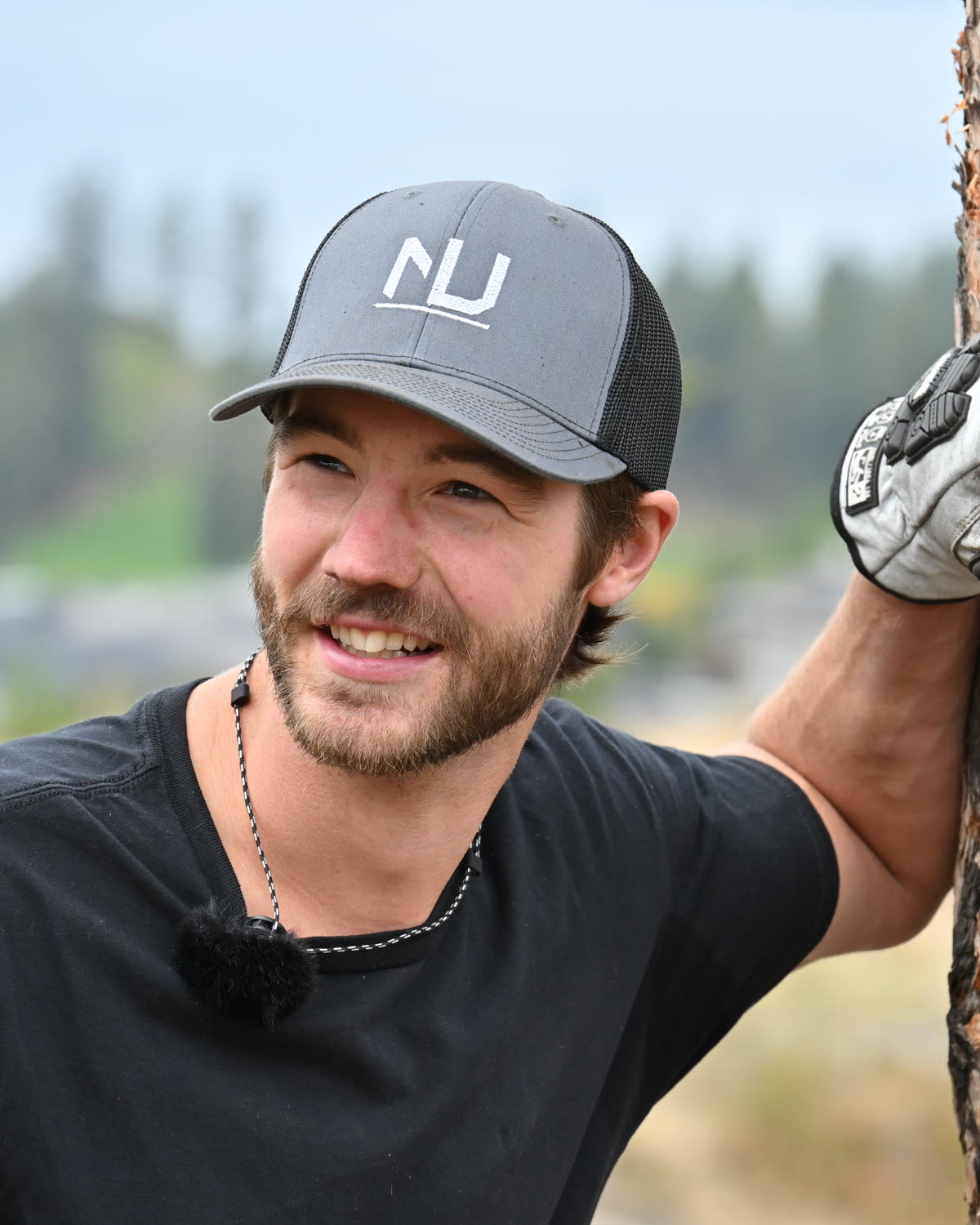Stephen in a Nether NU cap, leaning on a ponderosa pine above Okanagan Lake