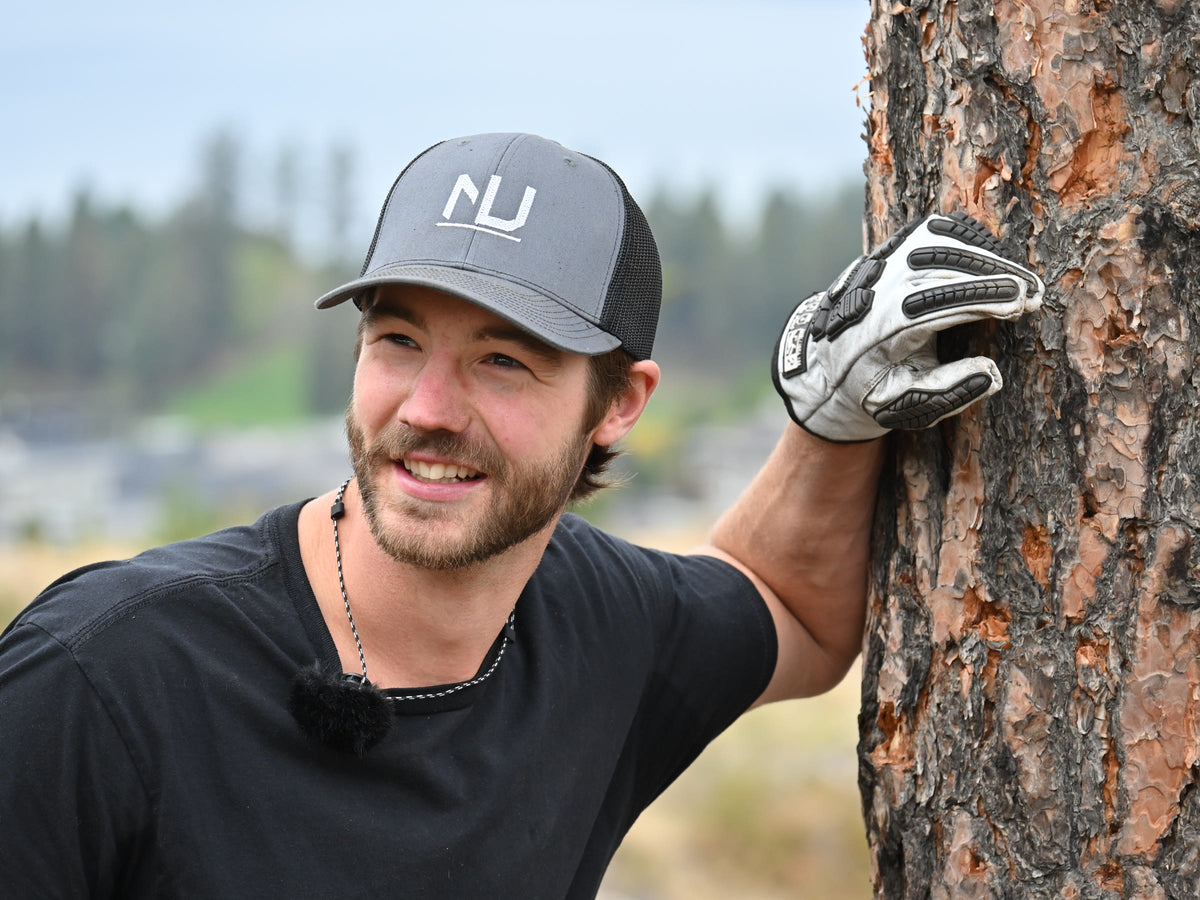 Stephen in a Nether NU cap, leaning on a ponderosa pine above Okanagan Lake