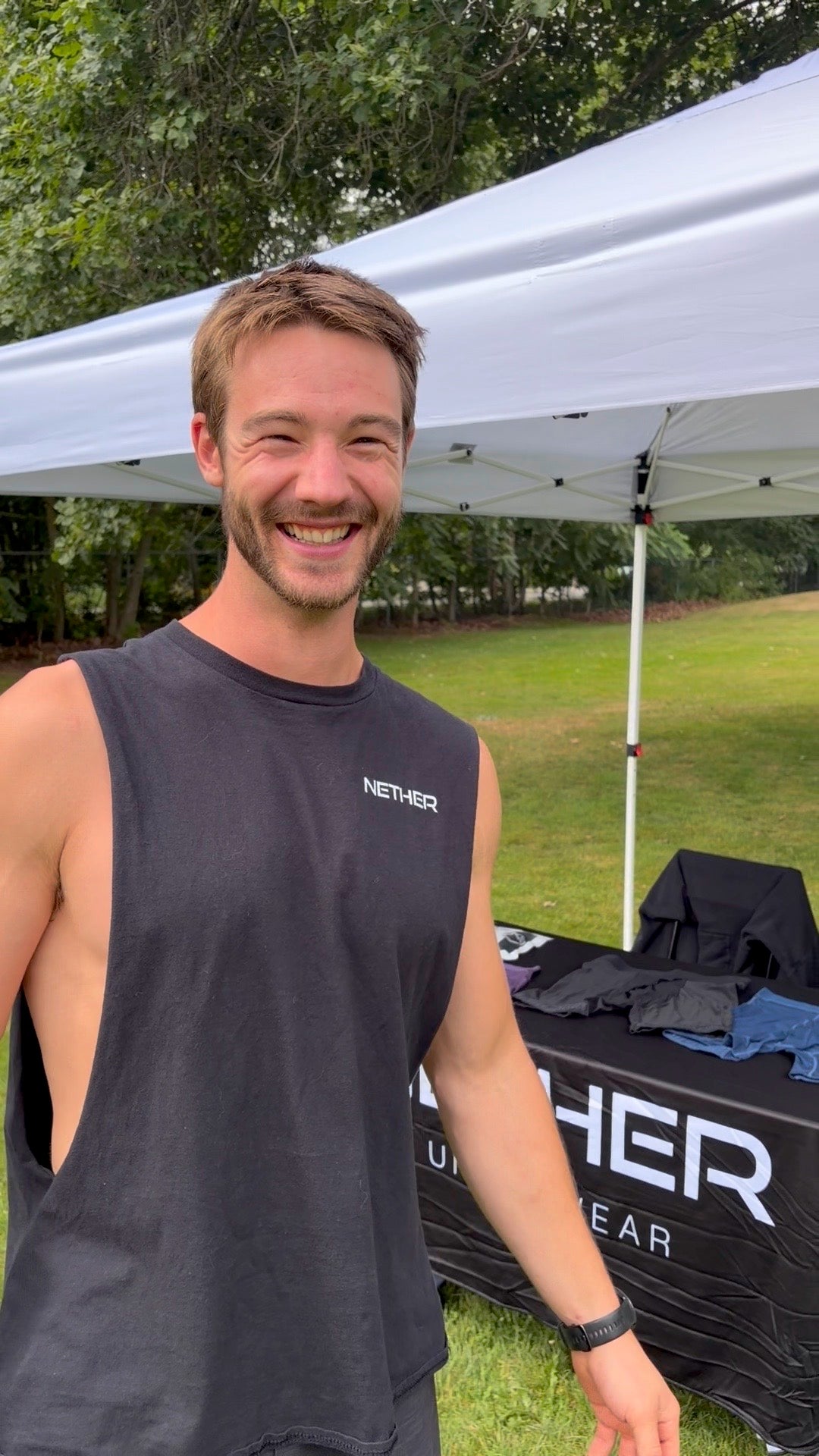 Nether founder Stephen Hiscock laughing beside the Nether Underwear stall at an outdoor market, boxer briefs folded on the branded table behind him